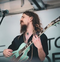 a man with long hair playing an electric guitar